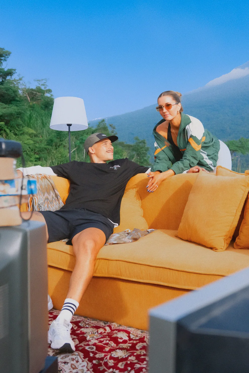 Friends in Bamboo Avenue clothing relaxing on an outdoor sofa under a blue sky